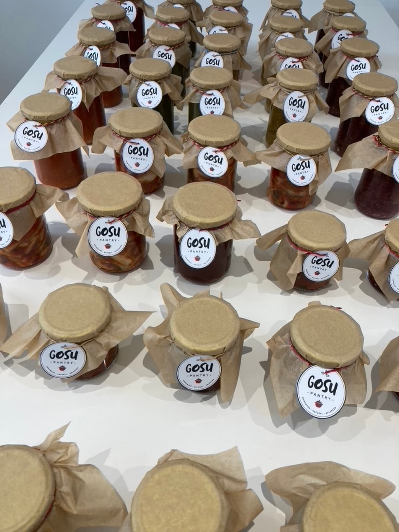 Rows of Gosu Pantry jars with brown waxed-paper tops